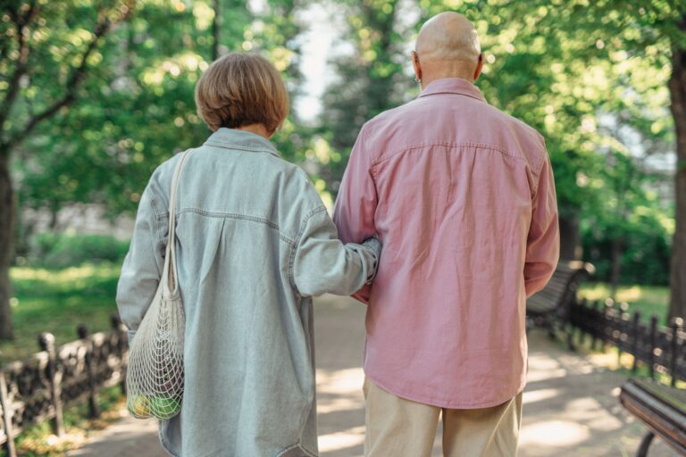 Older couple walking together in a park, representing mobility concerns and leg pain associated with peripheral artery disease.