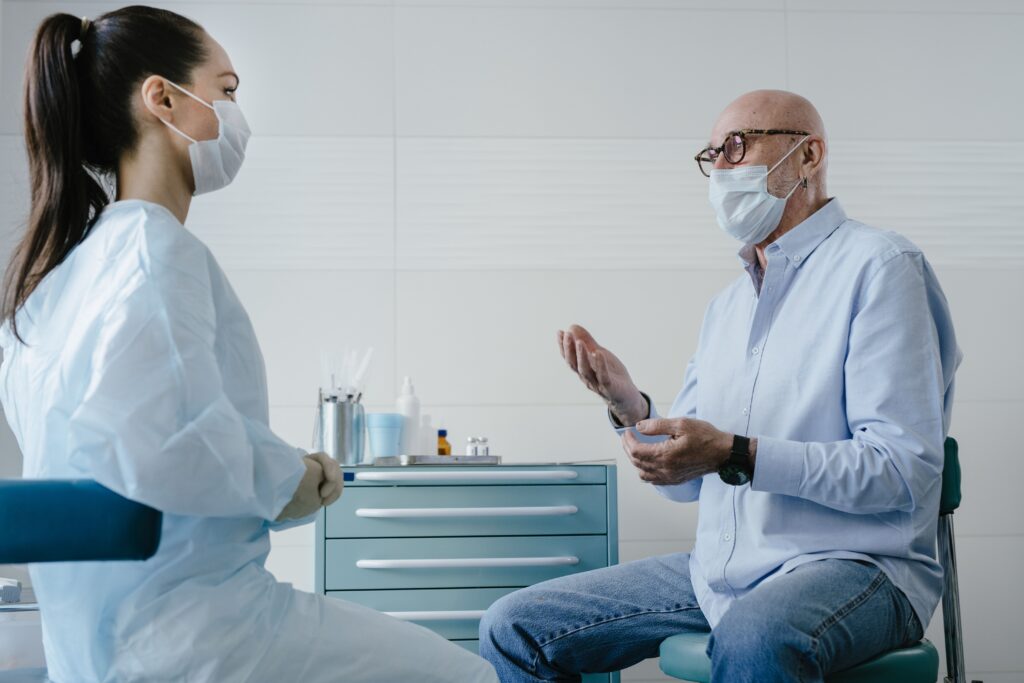 Older male patient discussing treatment options with a healthcare professional in a clinic.