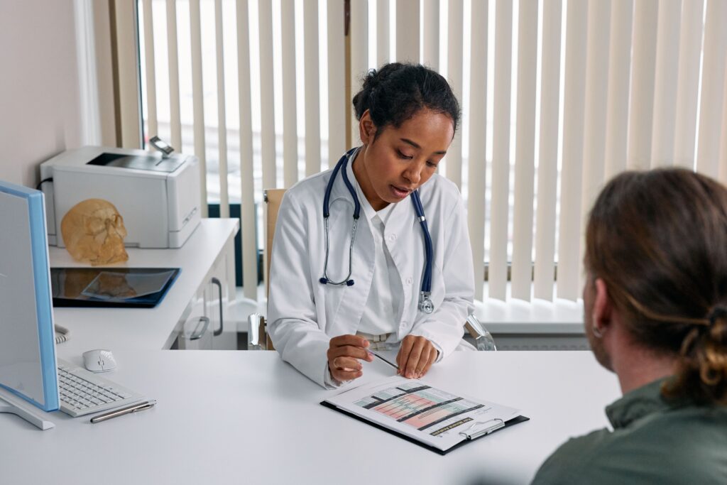 Doctor discussing treatment options with a male patient during a medical consultation for varicocele embolization.