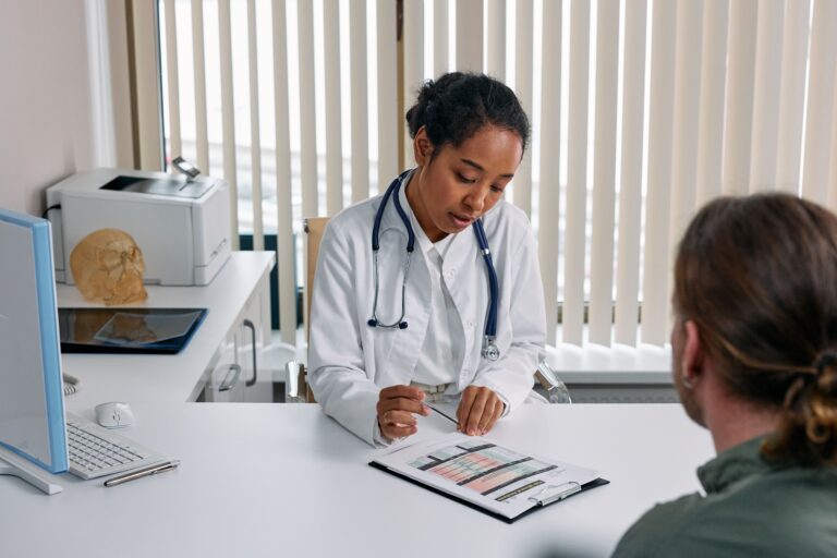 Doctor discussing treatment options with a male patient during a medical consultation for varicocele embolization.